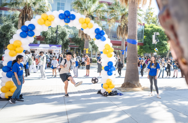 Student kicking a ball on the 7th Street Paseo during Homecoming festivities